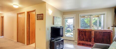 A living room with a television, a gray couch, and a wooden cabinet.