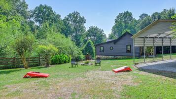 A house with a covered porch, a fenced yard, and two lawn chairs.