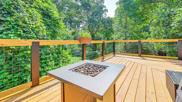 A wooden deck with a built-in fire pit and a seating area. - Cabin w/ Fire Pit - 7 Mi to Downtown Carrollton! (Carrollton)