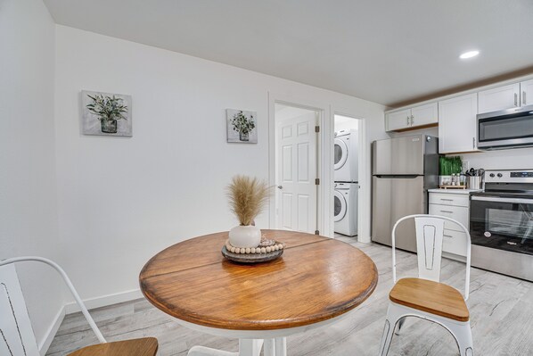 A modern kitchen with white cabinets, stainless steel appliances, and a wooden dining table with chairs. - Pet-friendly Home < 1 Mi to Downtown Moses Lake! (Moses Lake)