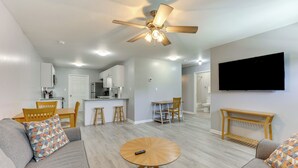 A modern living room with a gray sofa, a round wooden coffee table, and a ceiling fan. - 3 Mi to Brunswick Community College: Cozy Duplex! (Bolivia)