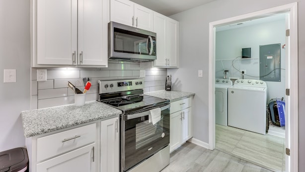 A compact kitchen with white cabinets, a stainless steel stove, and a microwave. - 3 Mi to Brunswick Community College: Cozy Duplex! (Bolivia)
