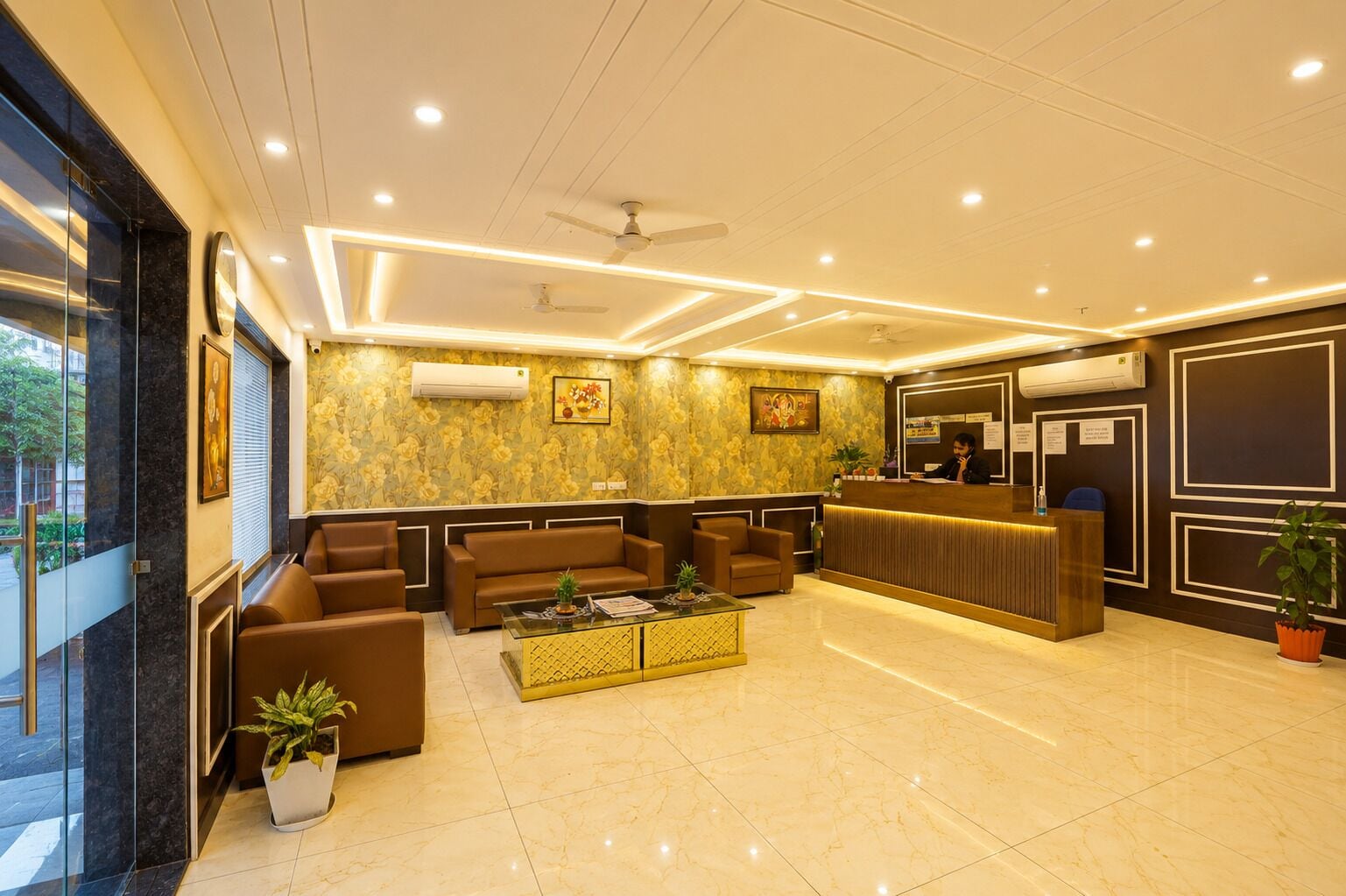 A hotel lobby with seating, a reception desk, and a ceiling fan.