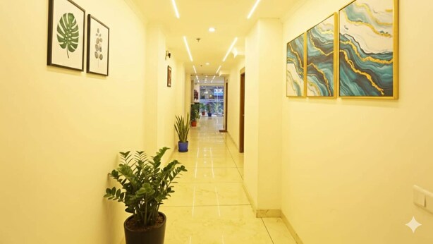 A hotel corridor with framed botanical prints, a potted plant, and abstract wall art. - Hotel Decent Suites - Delhi Airport (New Delhi)