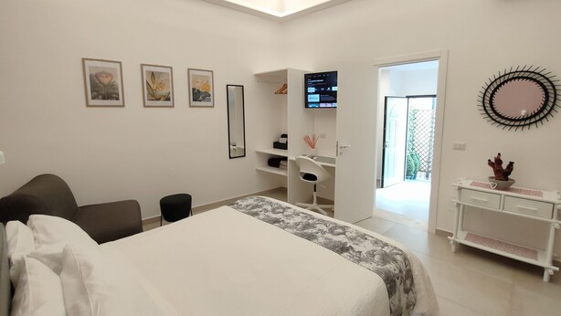 Une chambre moderne avec un grand lit, un bureau et un téléviseur. Les murs sont ornés de tableaux encadrés et il y a un miroir.