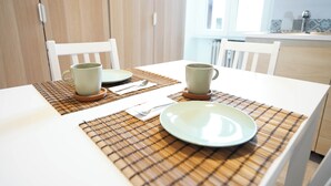 Une table à manger avec deux tasses, une assiette et une cuillère, disposés sur un set de table à carreaux.