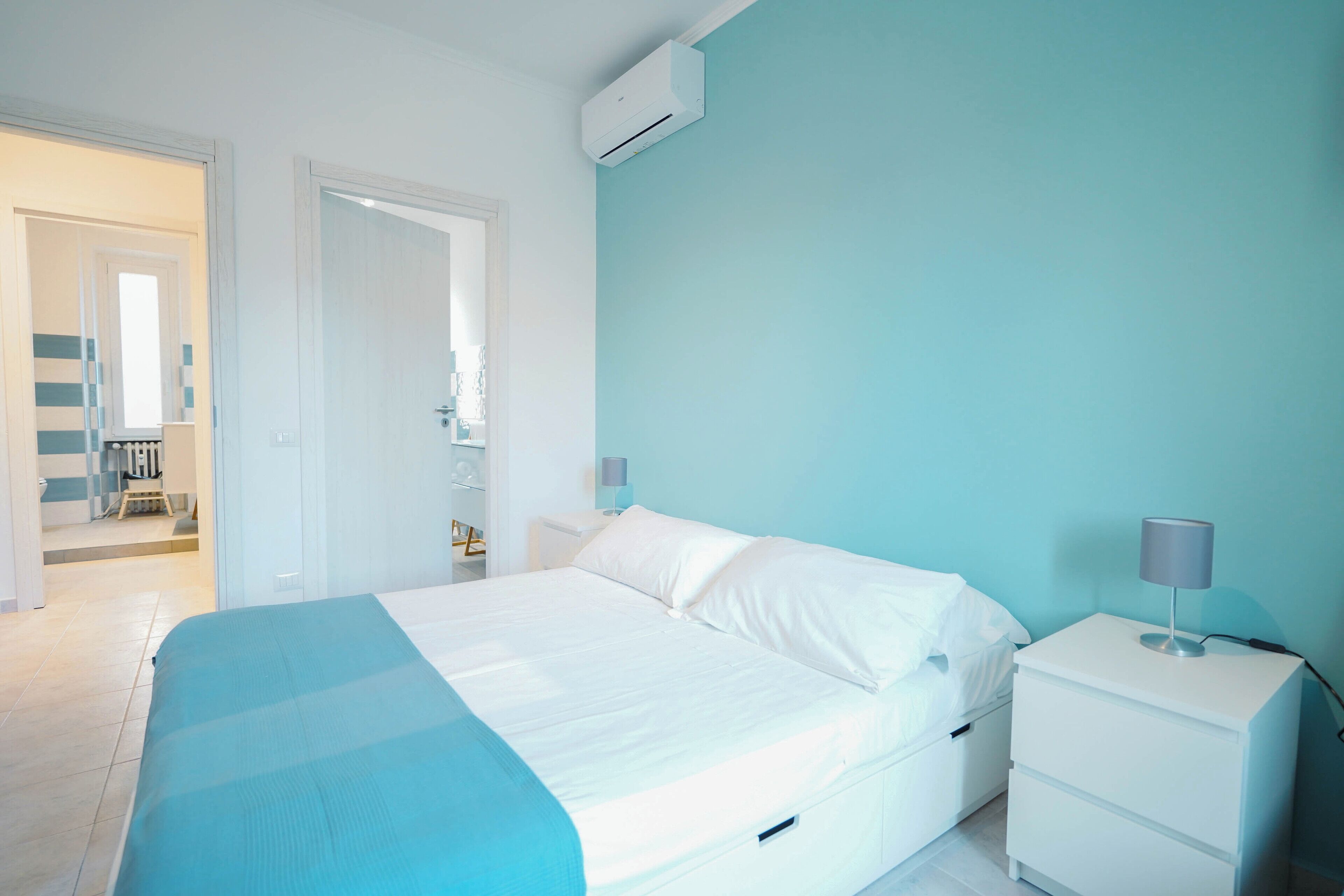 Une chambre à coucher comprenant un lit, des tables de chevet et un appareil de climatisation.
