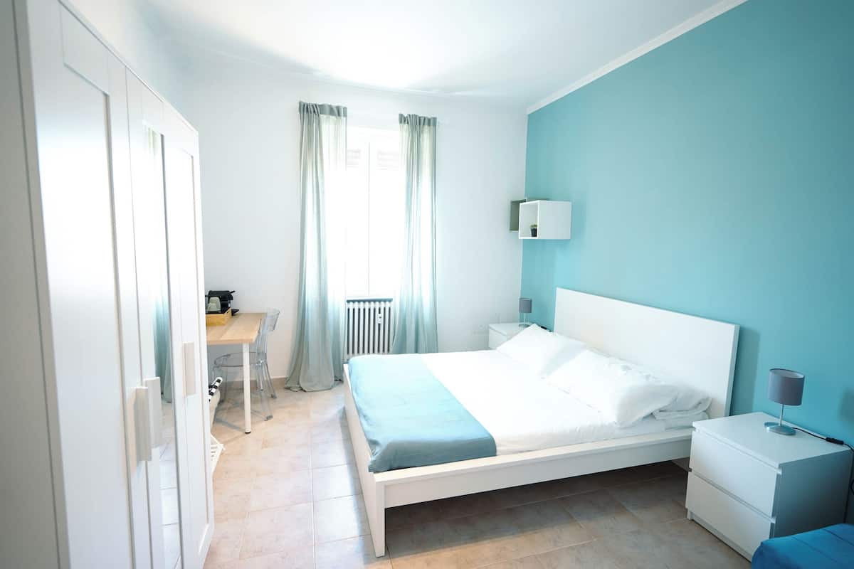A bedroom with a bed, bedside tables, a desk, and a chair.