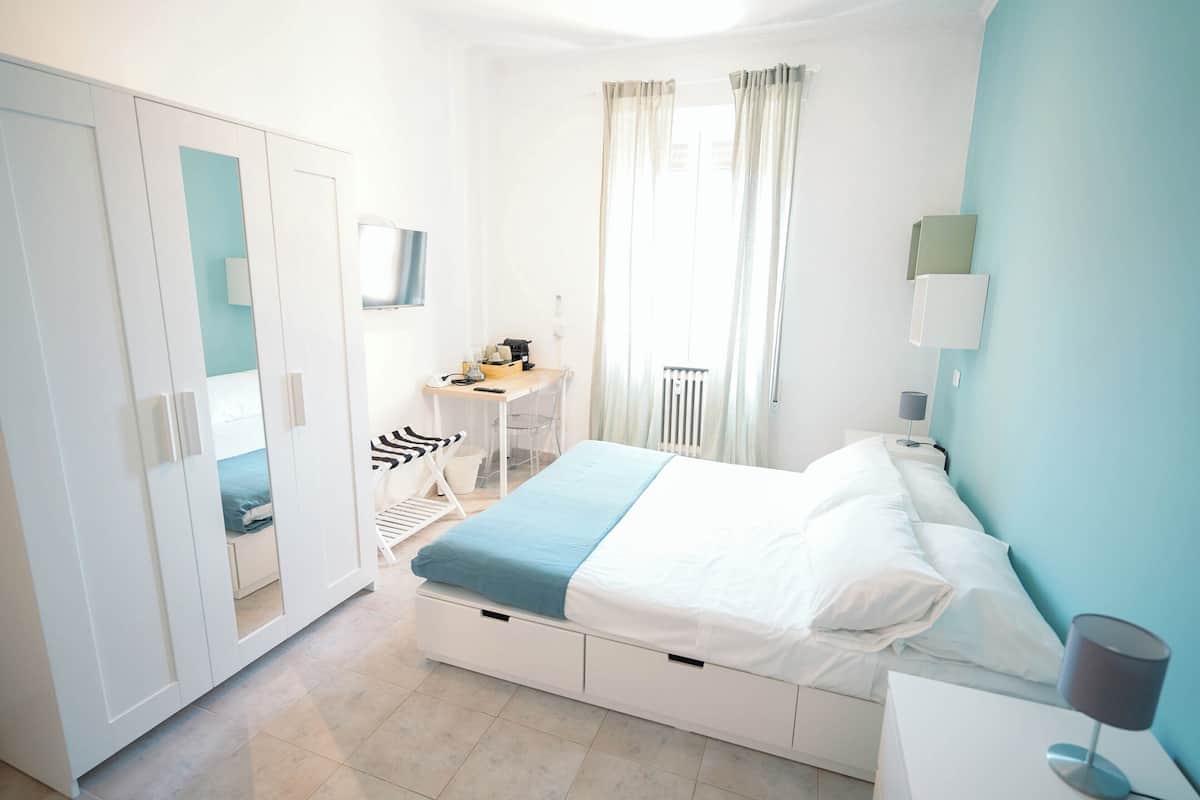 A bedroom with a bed, a desk, a chair, and a wardrobe.