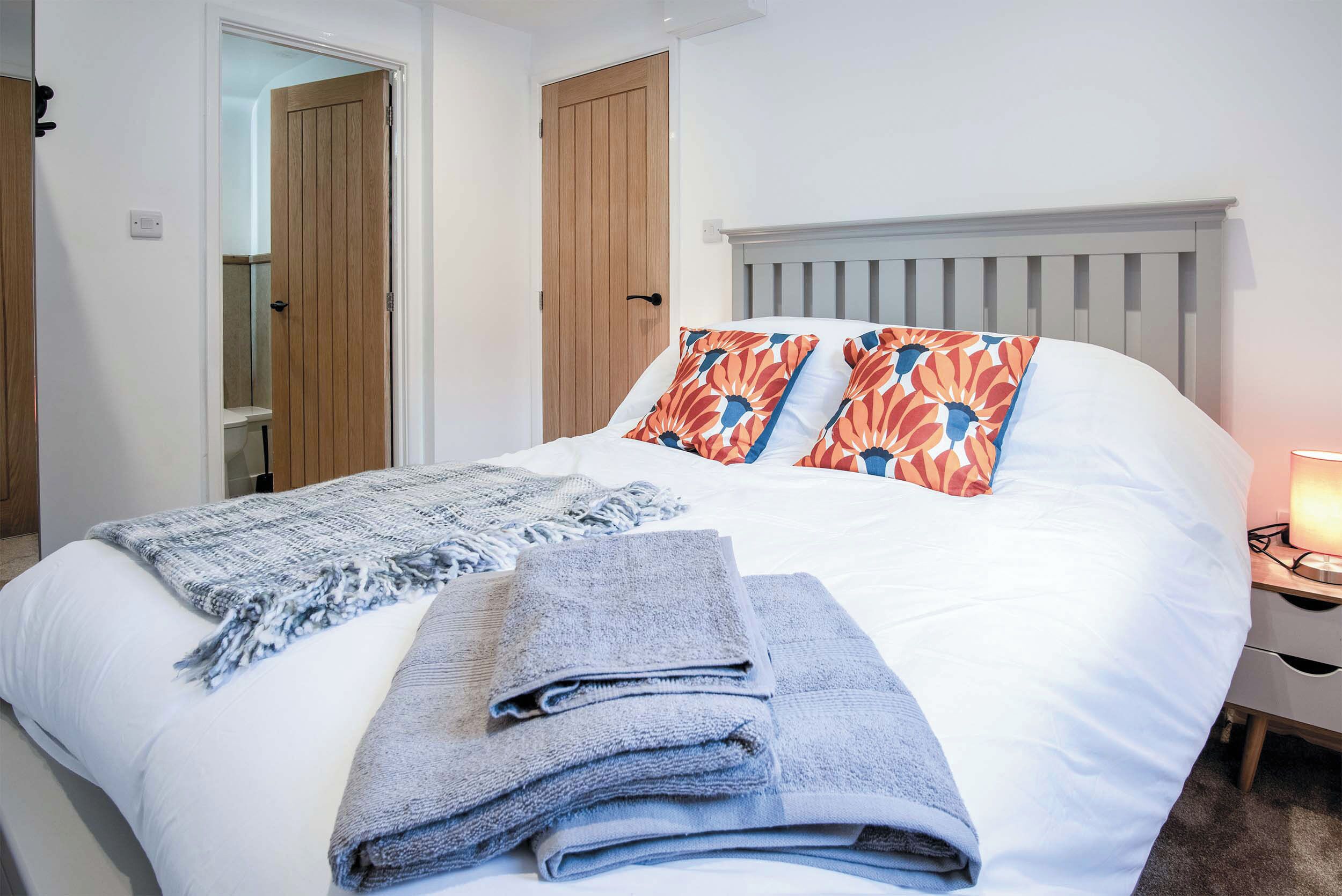 A bedroom with a bed, pillows, a blanket, and a nightstand.