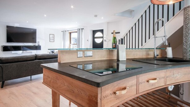 Una cocina moderna con una isla de madera, horno empotrado y un ventanal amplio.