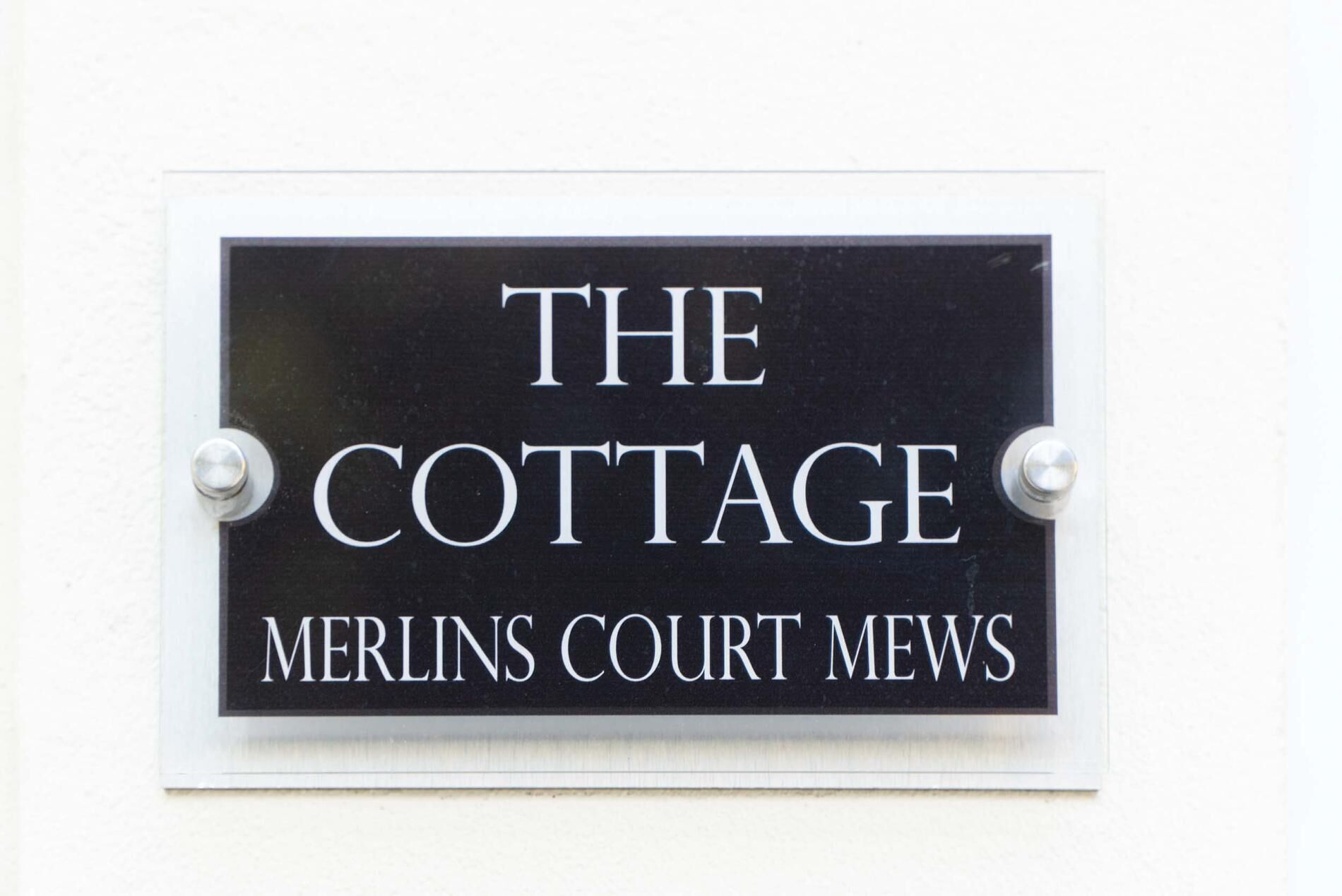 A sign with the text "THE COTTAGE MERLINS COURT MEWS".