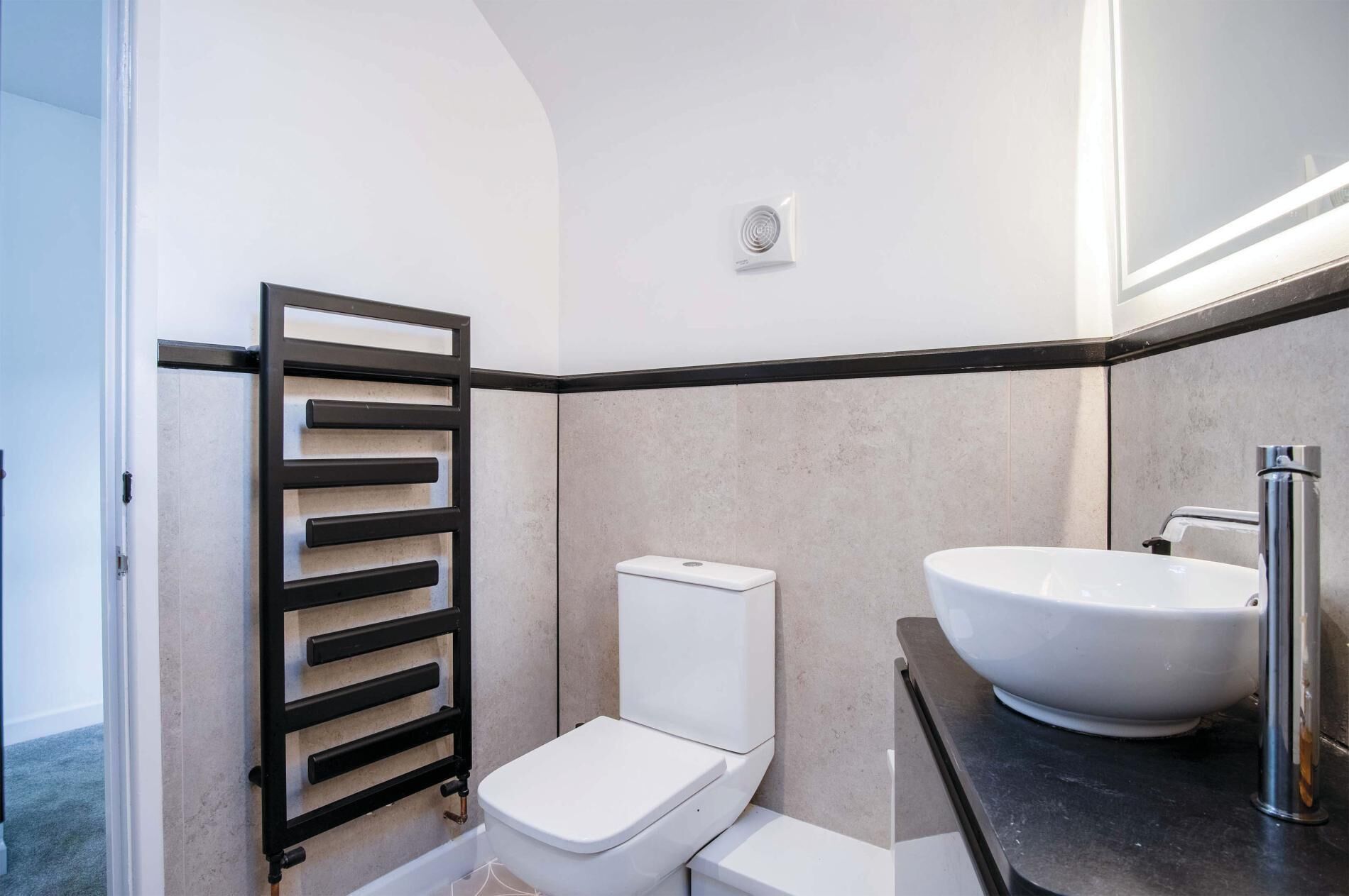 A modern bathroom with a toilet, a sink, and a towel rack.