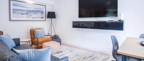 A modern living room with a sofa, armchair, and a dining table.