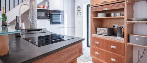 Une cuisine moderne équipée d’une cuisinière intégrée, d’une machine à café et de meubles de rangement en bois.