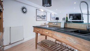 Una cocina moderna con una isla de madera, un lavaplatos empotrado y un ventanal grande.