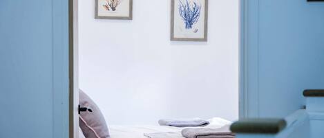 A bedroom with a bed, pillows, and two framed botanical prints on the wall.