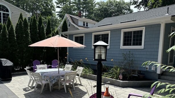 A patio with a table and chairs, a lamp post, and a covered area with an umbrella.