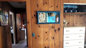 Ein Zimmer mit Holzwänden, einer weißen Kommode und einem gerahmten Bild von Meeresschalen.