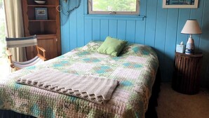 Ein Schlafzimmer mit Bett, Fenster, Holzschrank, Stuhl und Lampe.