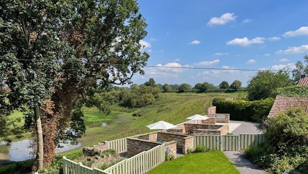 A courtyard with a brick patio, a wooden fence, and a large tree. - Moat Cottage - Luxury Country Cottage, Yorkshire Dales Views, Newby Hall Estate, Sleeps 4-5, Dog Friendly (Ripon)