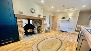 A cozy kitchen with a brick fireplace, wooden flooring, and a round rug. - Moat Cottage - Luxury Country Cottage, Yorkshire Dales Views, Newby Hall Estate, Sleeps 4-5, Dog Friendly (Ripon)
