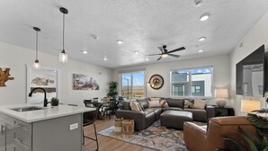 Uma sala de estar moderna com sofá, mesa de centro e um espaço de refeições com cadeiras e uma mesa.