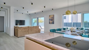 A modern kitchen with a marble countertop, a dining area with teal chairs, and a large window. - Villa Adria Dream by Litto (Kastela)