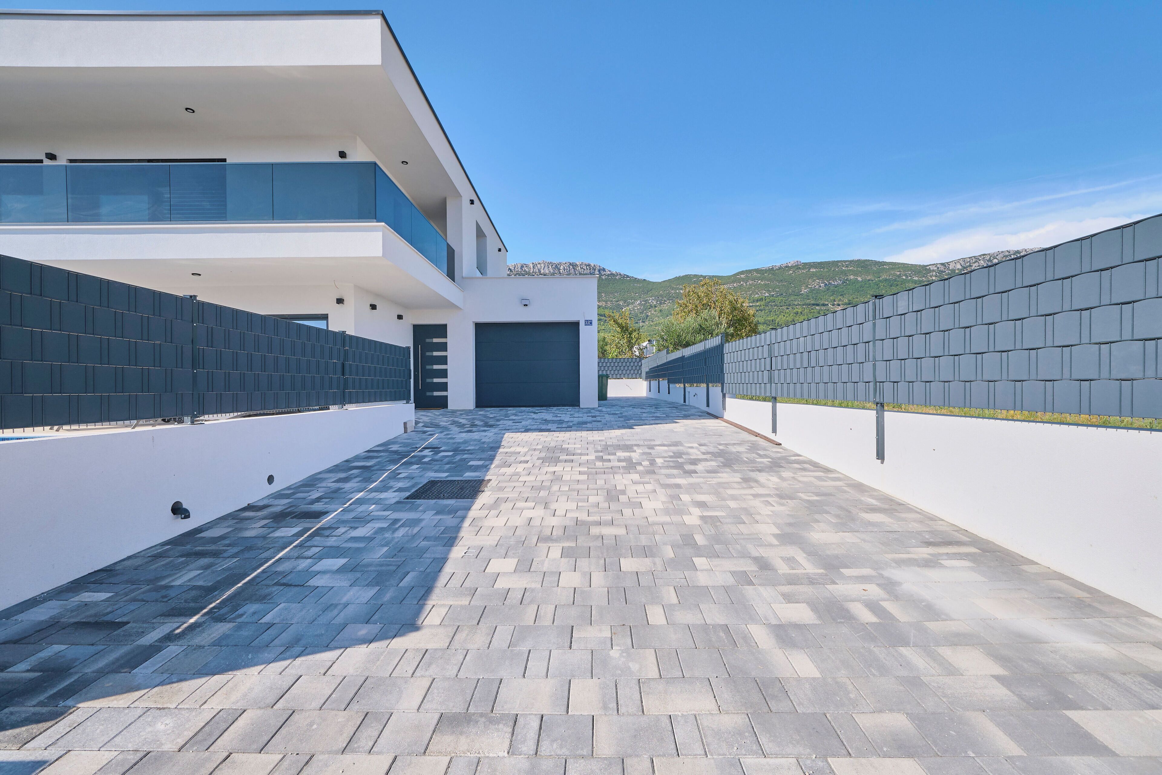 Un edificio moderno con techo plano, una galería techada y vistas a las colinas al fondo.