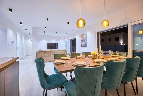 A modern dining area with a wooden table set for six, surrounded by teal chairs. - Villa Adria Dream by Litto (Kastela)
