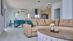 A modern living room with a beige sectional sofa, a round coffee table, and teal chairs. - Villa Adria Dream by Litto (Kastela)