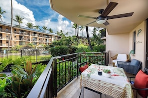 A balcony with a table, chairs, and a ceiling fan. - Kona Makai#1-102: Nearly Oceanfront, Ground Floor, with AC & Newly Remodeled! (Kailua Kona)