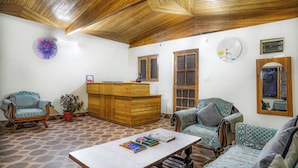 Amplia sala de estar con techo de madera, mostrador de recepción, mobiliario estampado y decoración en las paredes.