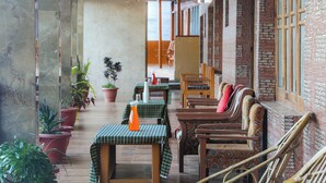 Un restaurante con mesas y sillas de madera, plantas en macetas y paredes de ladrillo.