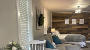 A modern living room with a sectional sofa, a dining table with placemats, and a decorative plant. - Charming and immaculate 1-bedroom Suite/Apartment in Elizabethton  (Elizabethton)
