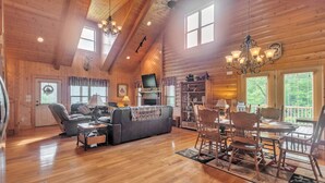 A spacious living room with a fireplace, a television, and a dining area with wooden chairs and a table.