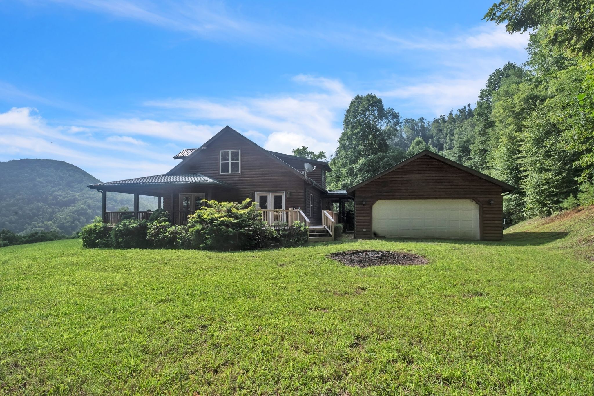 A two-story log cabin with a covered porch and a garage.