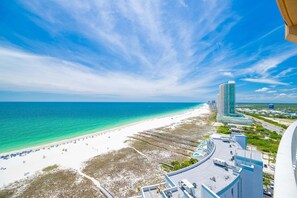 Una playa con un hotel, cielo azul claro y océano.