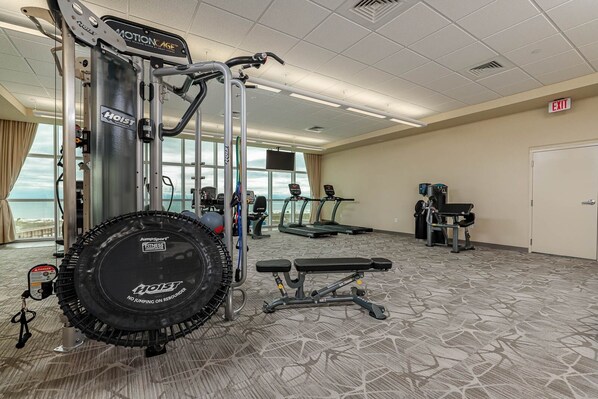 Un gimnasio con cintas de correr, una bicicleta estática y un banco para pesas.
