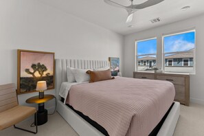 Relax in a spacious room with a large bed, tufted headboard, and a wooden nightstand.