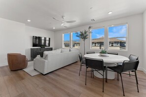 Relax in this stylish space with a central sofa, armchair, and dining area featuring a round table and chairs.