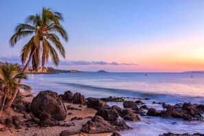 A beach with palm trees, rocky shoreline, and calm sea. - Pacific Shores A212 2 Bedroom Condo (Kihei)