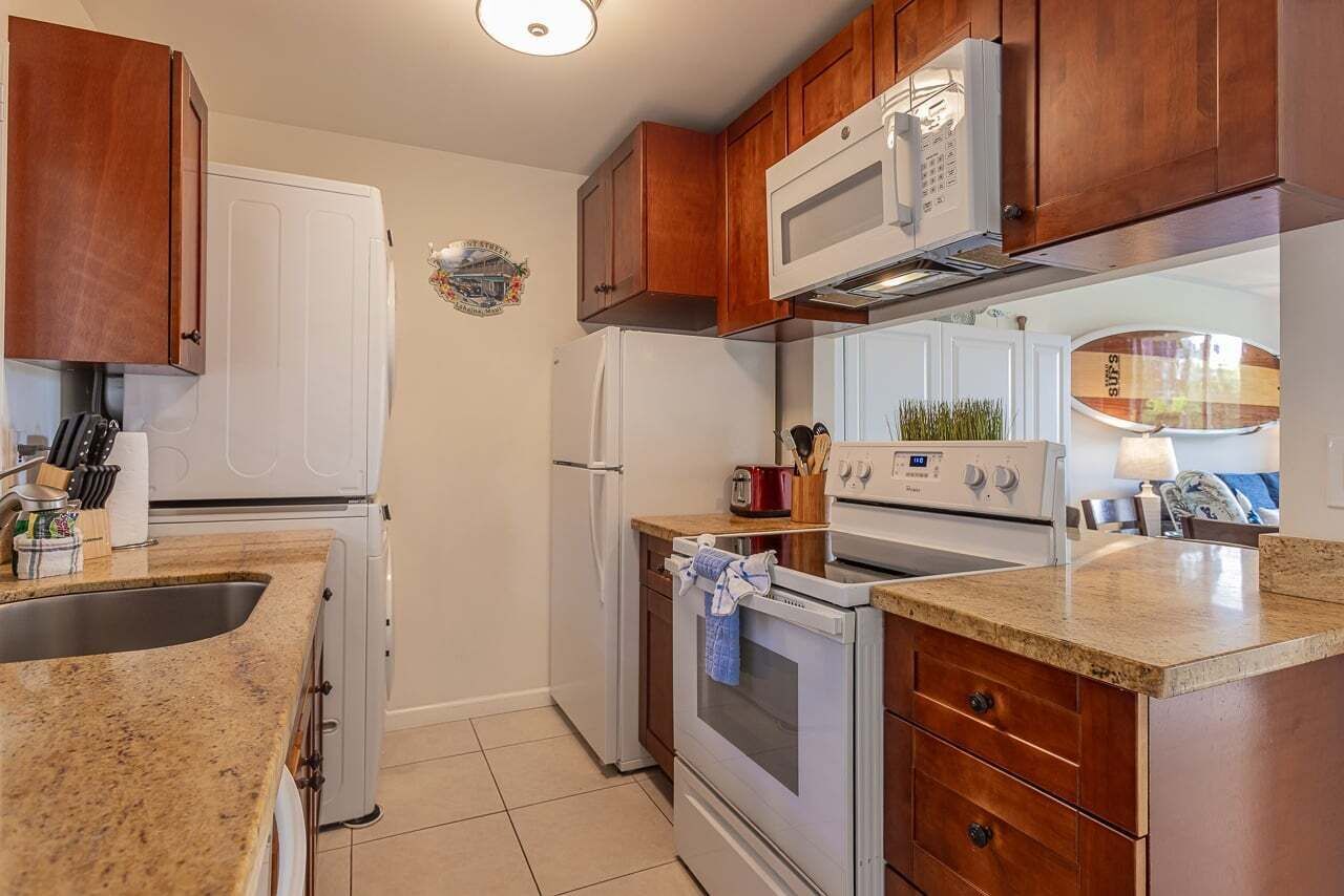 A kitchen with wooden cabinets, a microwave, a refrigerator, an oven, and a sink.