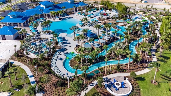 An aerial view of a resort with multiple swimming pools, palm trees, and a large central pool.