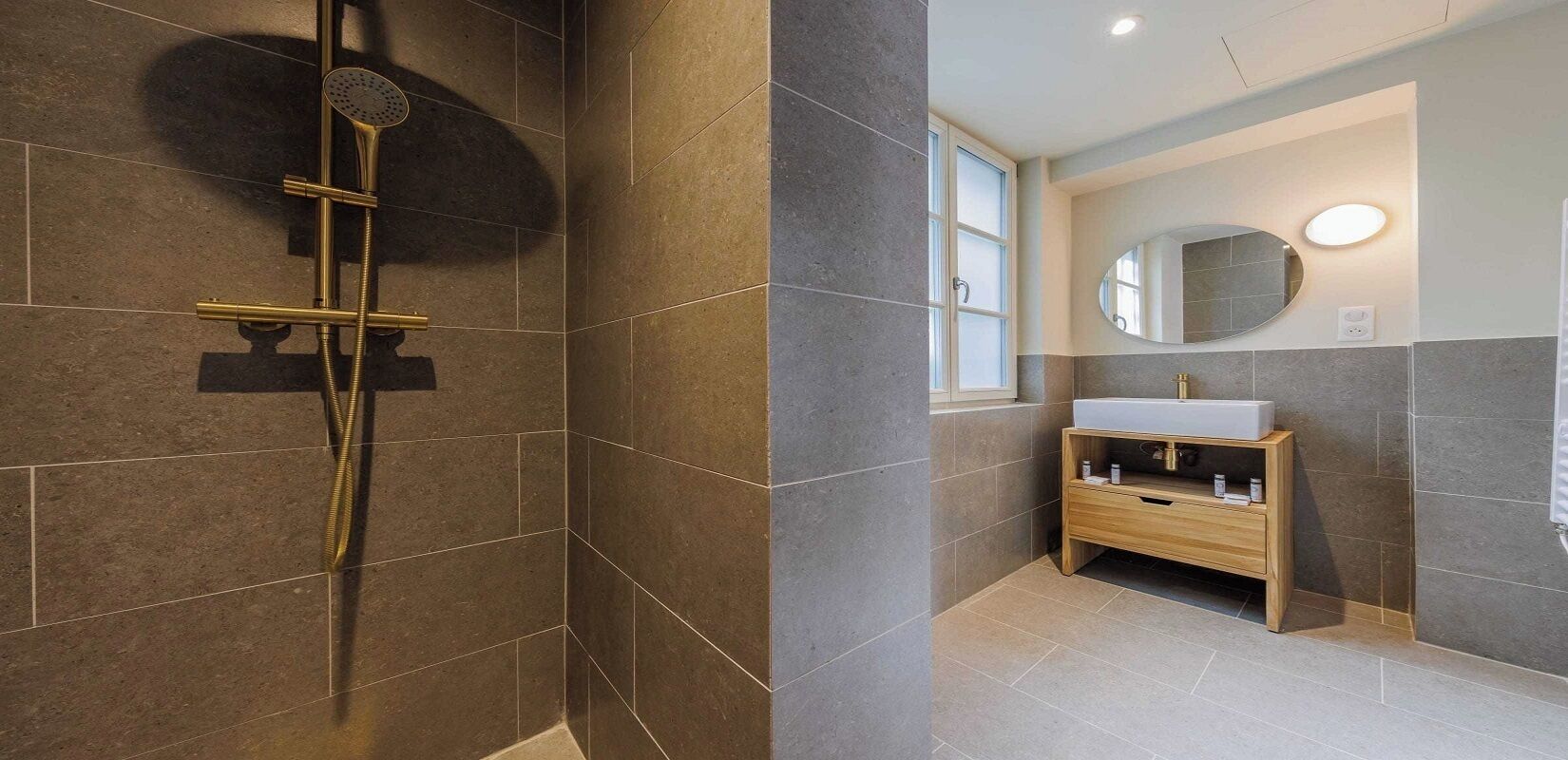 A modern bathroom with a shower, vanity, and a large mirror.