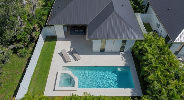 Une maison moderne dotée d’une piscine, de deux chaises longues et d’une pelouse bien entretenue.