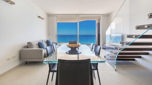A modern living room with a glass table, a sofa, and a view of the sea. - 4009 Attico Smeraldo by Perle di Puglia (Gallipoli)