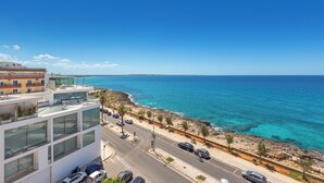 A coastal road with a modern building featuring large windows and a balcony overlooking the sea. - 4009 Attico Smeraldo by Perle di Puglia (Gallipoli)