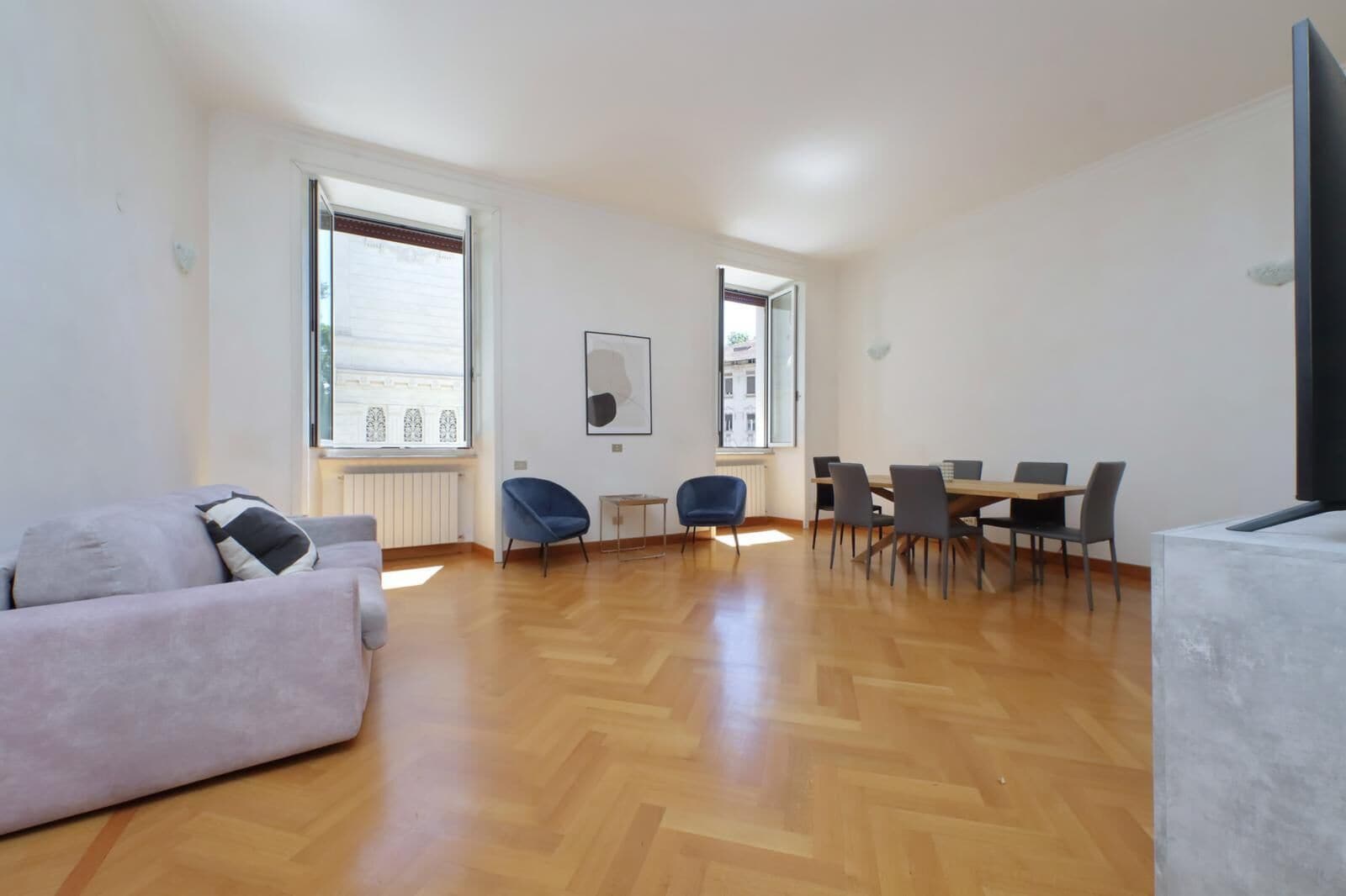 Un amplio espacio habitable con sofá, mesa de comedor, sillas y televisor.