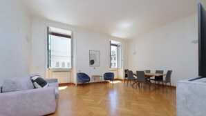 A spacious living area with a sofa, dining table, chairs, and a TV. - Exclusive Historic Ghetto Flatinrome (ROMA)